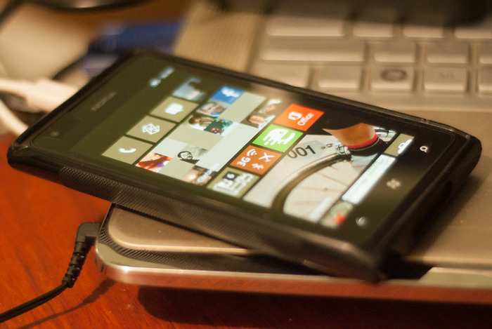 Smartphone displaying app tiles on screen, resting on laptop keyboard, symbolizing people learning interesting facts online.