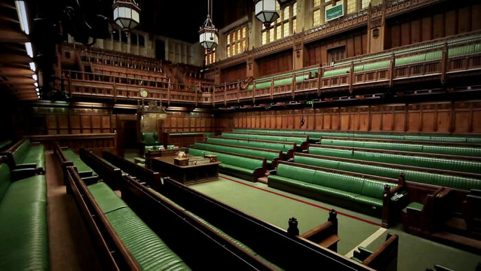 Empty courtroom with green benches and wooden paneling, illustrating crime and legal consequences discussed in online group.
