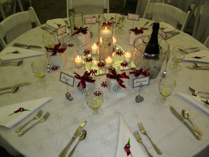Wedding reception table with candles and champagne, themed with red ribbons, reflecting a festive celebration setting.