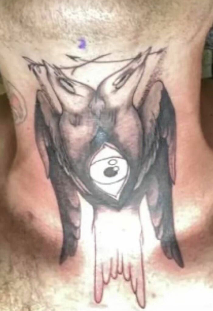 Unusual tattoo of mirrored black birds with an eye symbol on a person's neck.