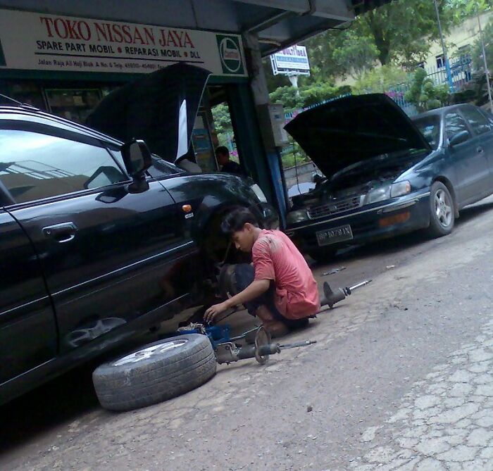 Mechanic working on car repair outside a Nissan spare parts shop, illustrating entertaining it doesn’t work like that stories.