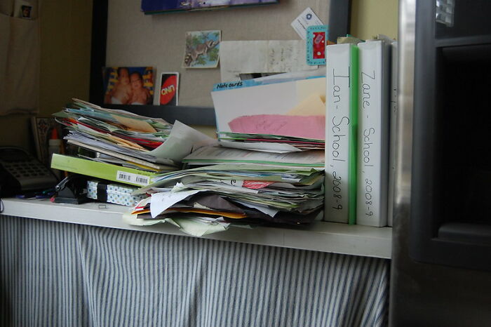 Cluttered office shelf with piles of papers and binders, illustrating disorganized work environment in professional stories.