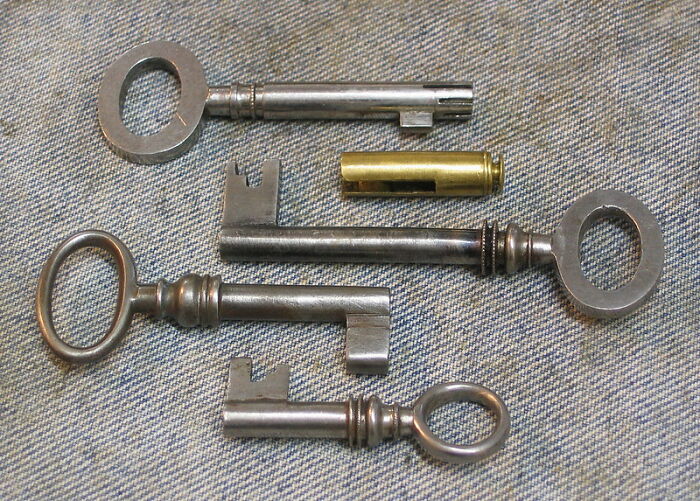 Set of vintage metal keys and a brass lock cylinder arranged on fabric, illustrating it doesn't work like that concept.