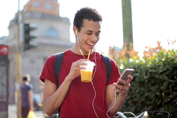 Man wearing red shirt drinking and watching phone