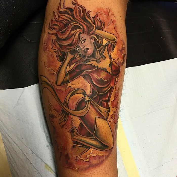 Marvel tattoo depicting a female superhero Dark Phoenix surrounded by flames on a person's leg.