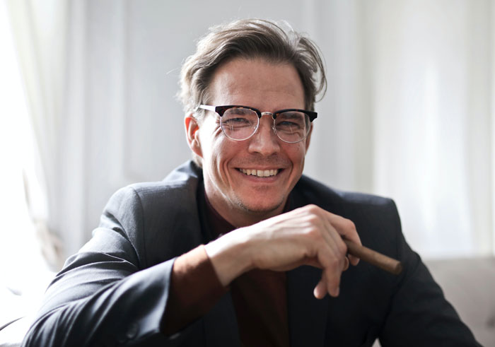 Man wearing suit smiling and holding cigar