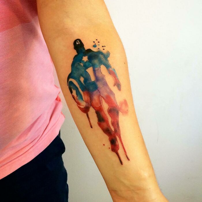 Marvel tattoo of Captain America in watercolor style on forearm.