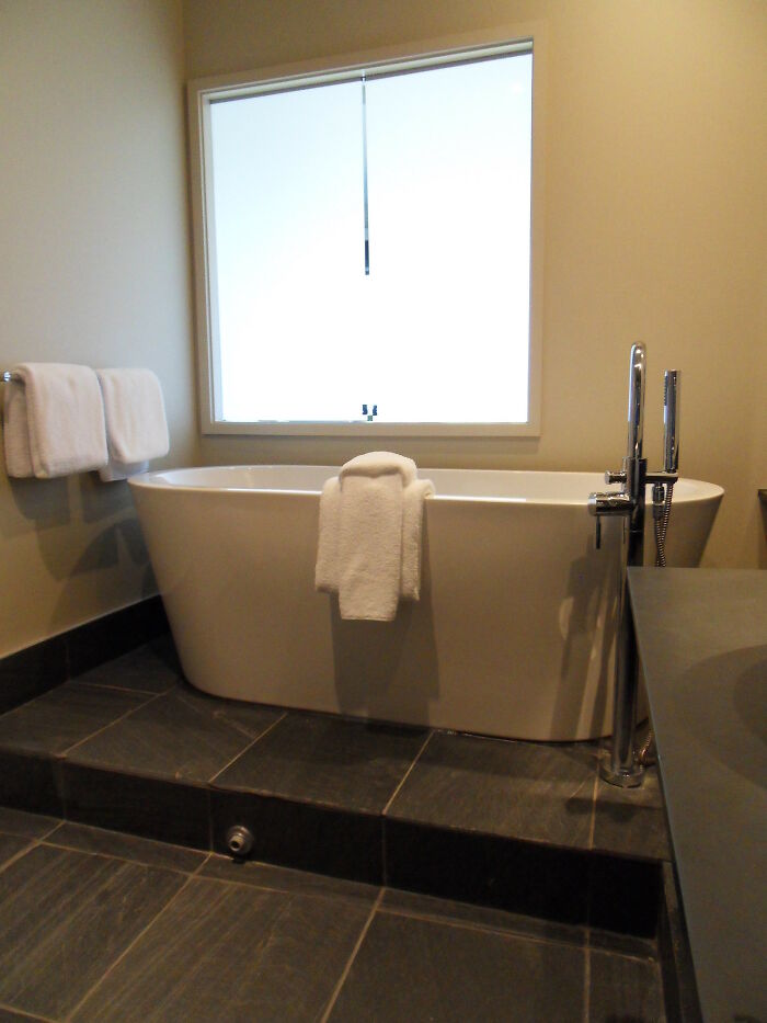Modern bathroom with a white bathtub and towels, illustrating things you may not think of doing but could be a crime.