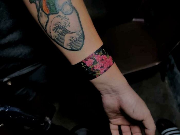 Colorful floral armband tattoo design on forearm, showcasing creative ink art ideas and meanings.