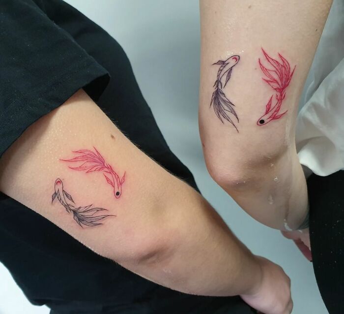 Minimalist tattoos of matching colorful fish on two arms symbolize a strong friendship.