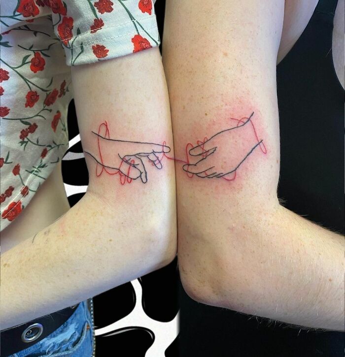 Two arms with matching BFF tattoos of hands linking fingers, representing friendship.