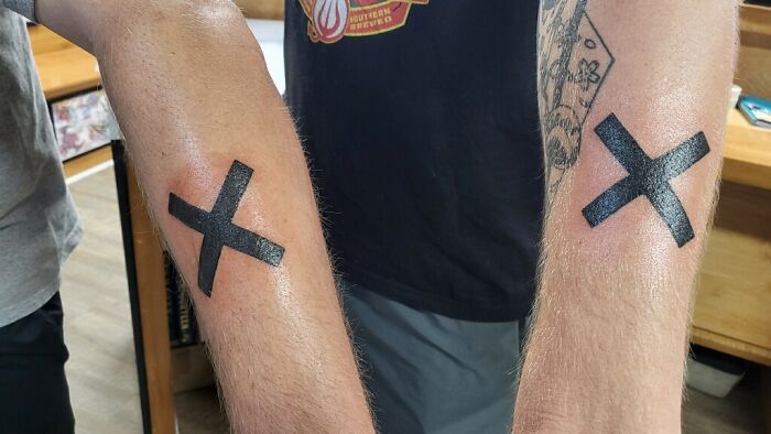 Matching X tattoos on two forearms symbolize a best friend bond.