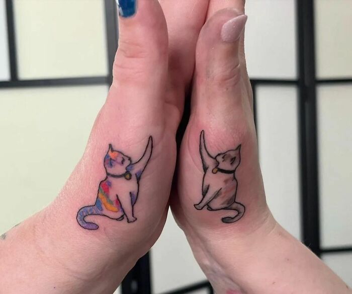Two hands with matching BFF tattoos of colorful cats on the sides, symbolizing friendship.