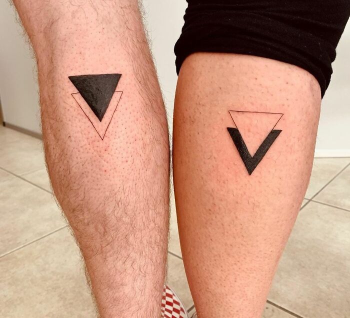 Matching BFF triangle tattoos on legs, one filled with black ink, representing friendship and unity.