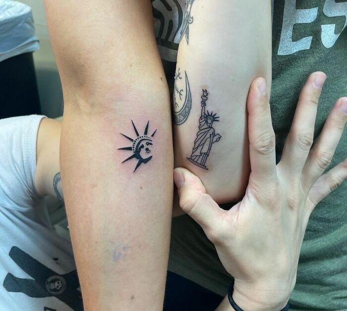 Friend tattoos of the Statue of Liberty on forearms, symbolizing enduring friendship.
