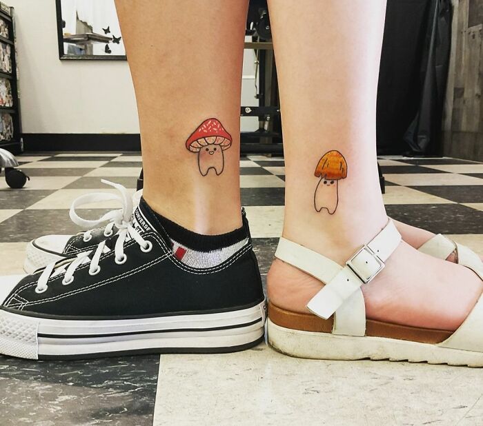 Cute best friend tattoos of mushrooms on calves, one in red and one in orange, symbolizing friendship.