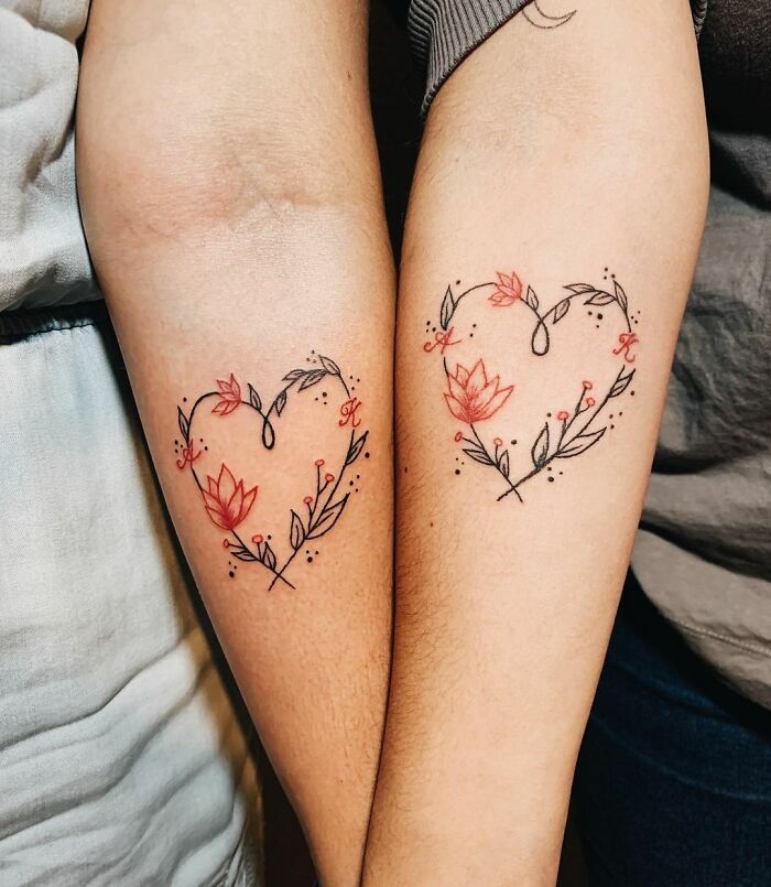 Matching floral heart tattoos on forearms symbolizing friendship.