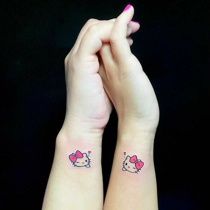 Two wrists with matching best friend tattoos of Hello Kitty, symbolizing friendship.