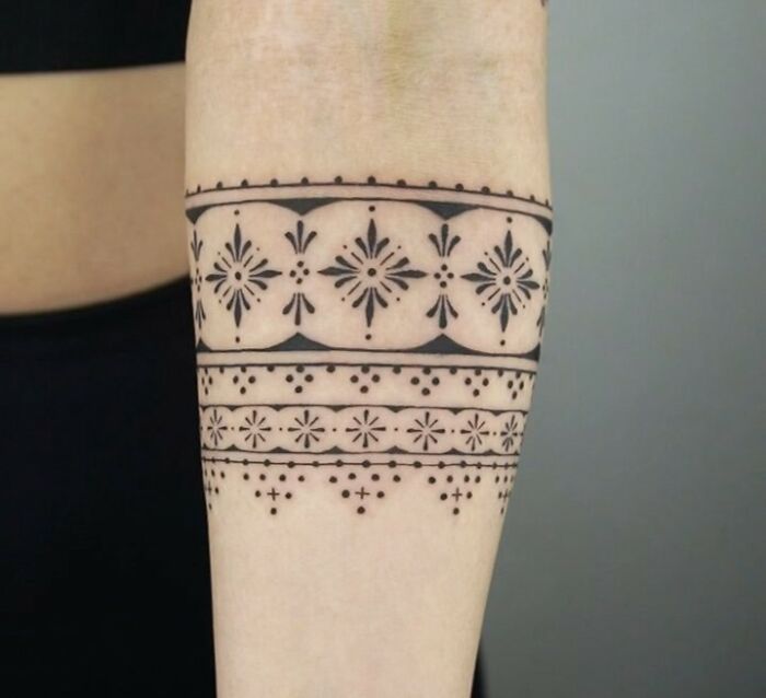 Geometric armband tattoo design with intricate patterns on forearm.