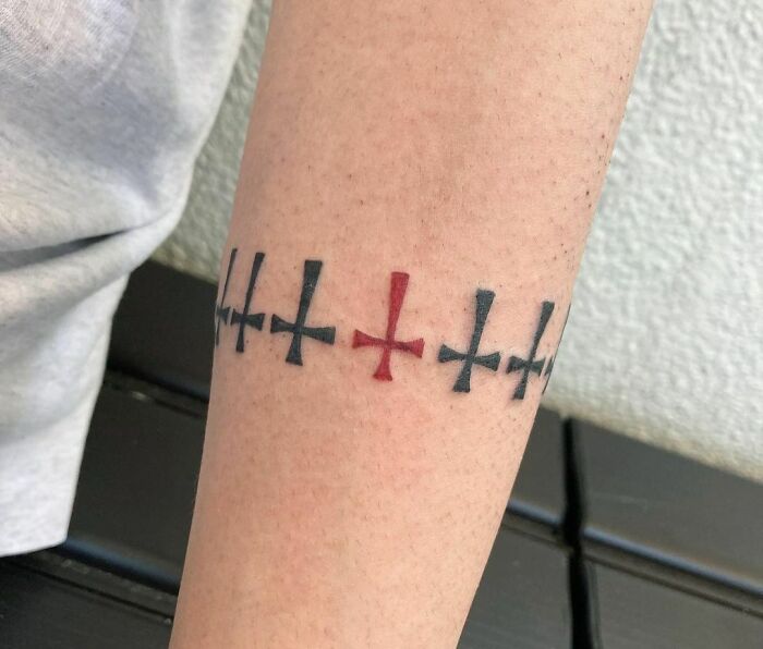Armband tattoo featuring a pattern of black and red crosses on an arm.