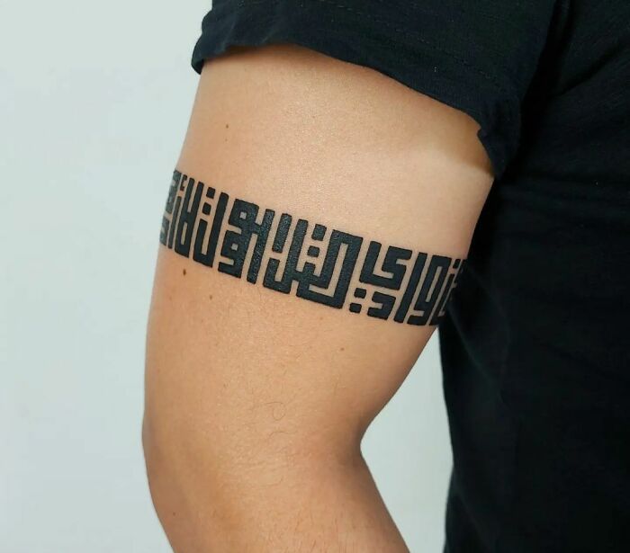 Geometric armband tattoo design on upper arm, showcasing intricate patterns and bold artistry.