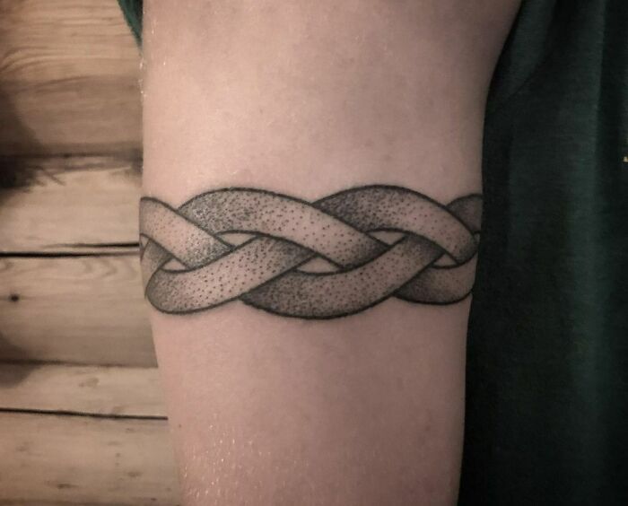 Intricate woven armband tattoo design on the upper arm, showcasing unique tattoo art.