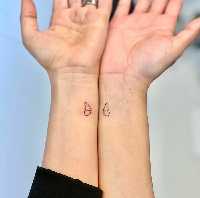 Minimalist matching BFF tattoos of butterfly wings on wrists.