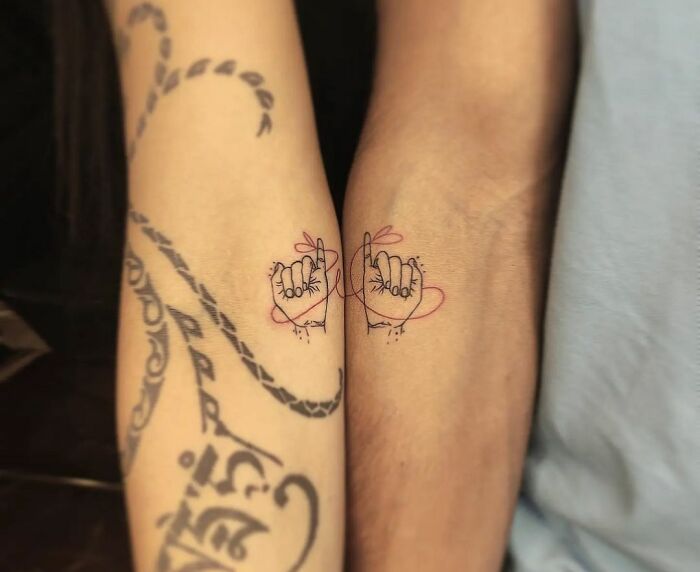 Friendship tattoos featuring pinky promise designs on two forearms, symbolizing a special bond between best friends.