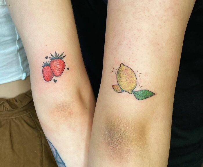Tattoos of a strawberry and lemon on forearms symbolize friendship.