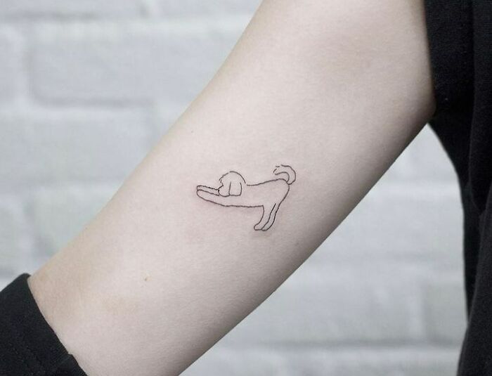 Minimal tattoo of a playful dog on forearm, showcasing a simple yet artistic design.