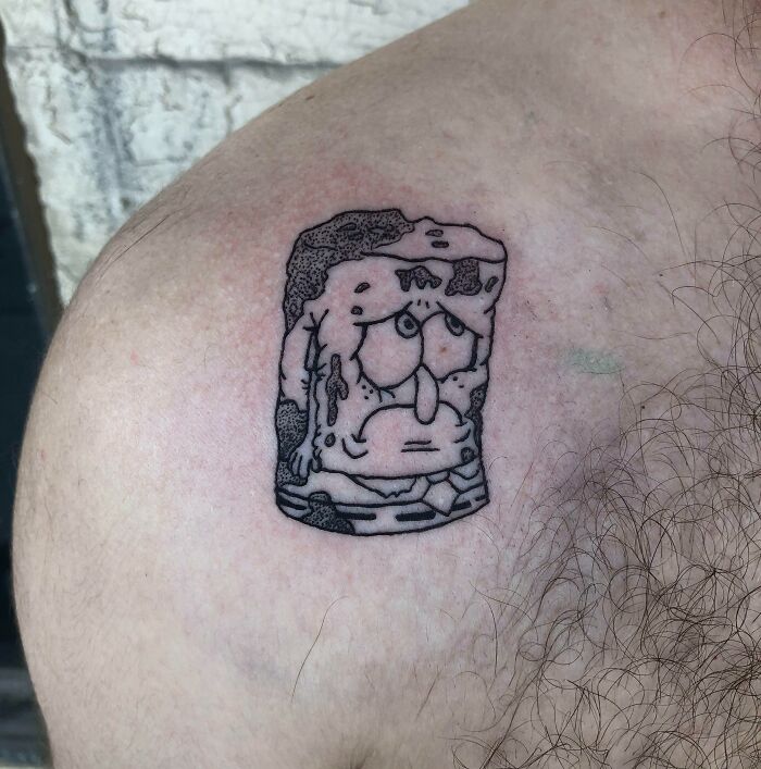 Cartoon-inspired tattoo depicting a melting sponge character from a famous animated show on a person's shoulder.
