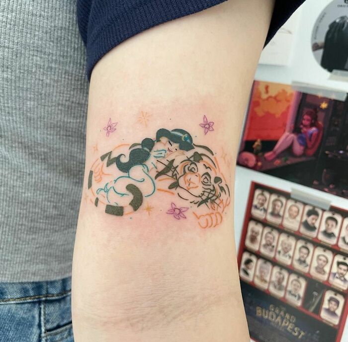 Cartoon tattoo with nostalgic characters on an arm, featuring vibrant colors and playful design elements.