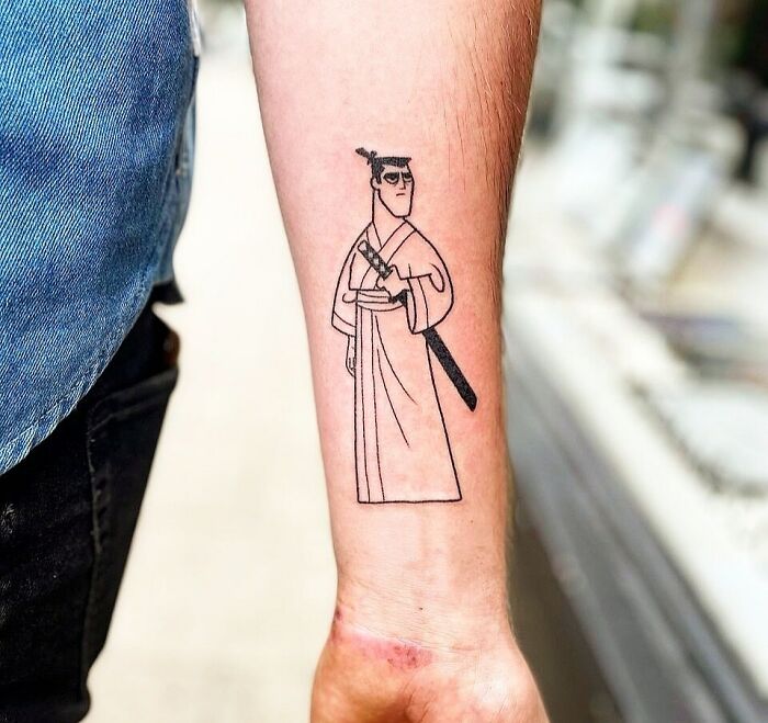Cartoon tattoo of a samurai character Samurai Jack on a forearm, showcasing nostalgic design.