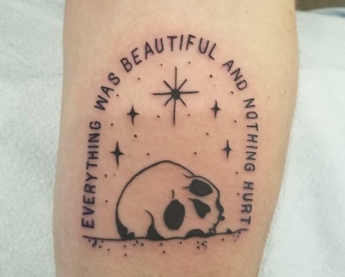 Word tattoo featuring a skull and stars, with text "Everything was beautiful and nothing hurt" on skin.
