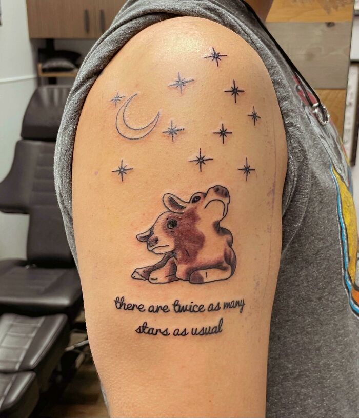 Tattoo of a cow and moon with stars, surrounded by inspirational words, showcasing unique word tattoos.