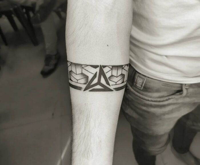 Geometric armband tattoo design on forearm, featuring bold lines and shapes.