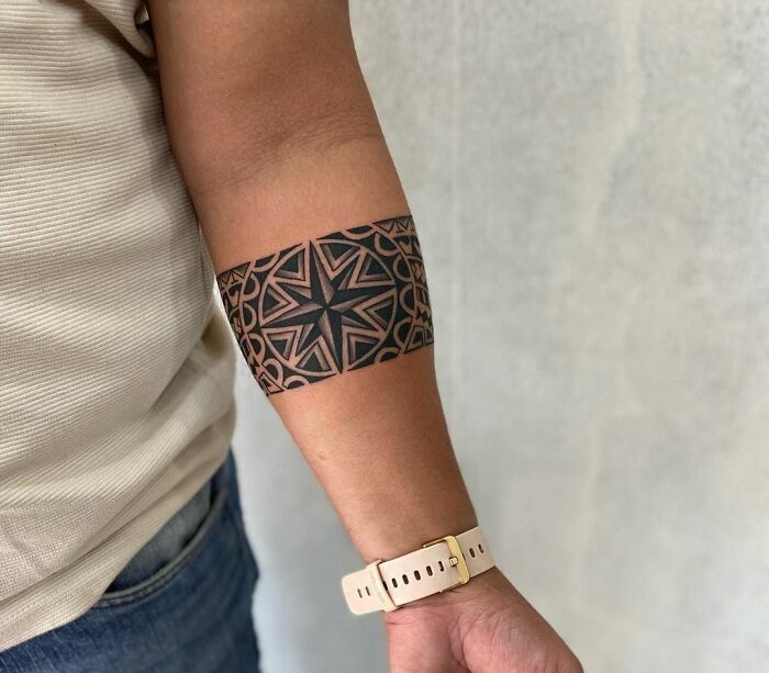 Geometric armband tattoo on a person's forearm, showcasing intricate design details.