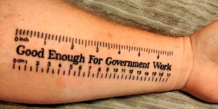 Tattoo of a ruler with the words "Good Enough For Government Work" on an arm.