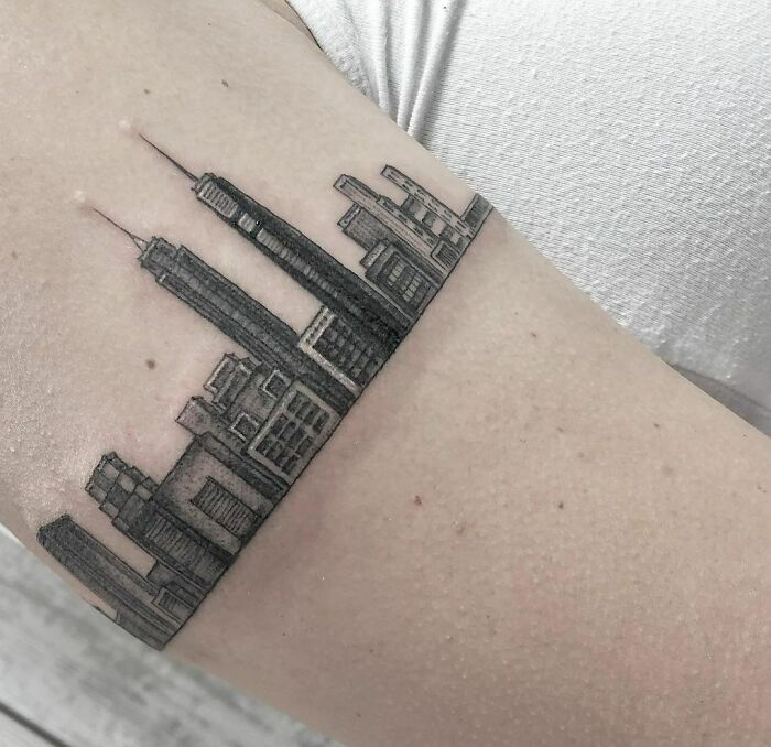 Armband tattoo featuring a detailed city skyline design on an arm.