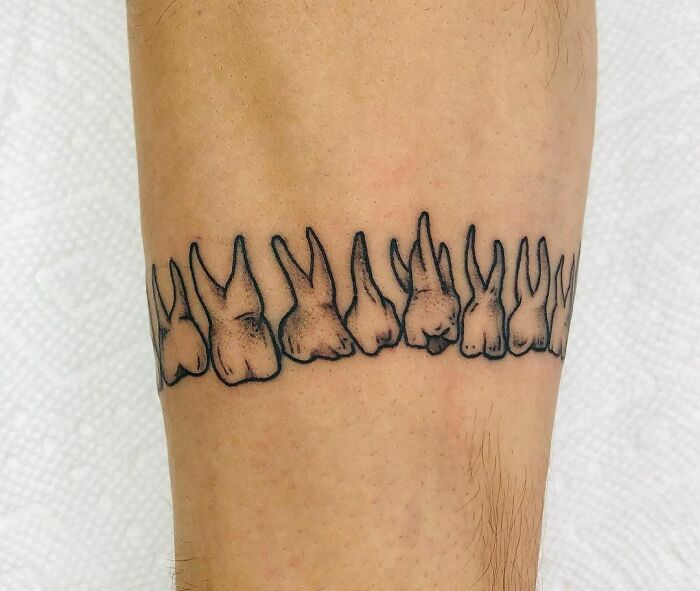 Armband tattoos with rabbit ears design on forearm.