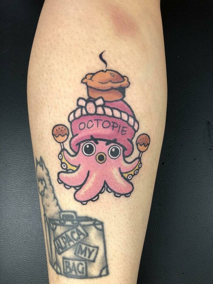 Octopus tattoo with a cupcake hat labeled "Octopie" on forearm, showcasing creative word tattoo art.