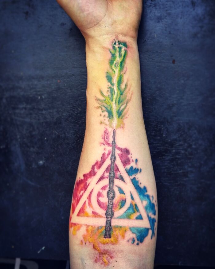 Watercolor tattoo with vibrant colors and a geometric design on an arm, showcasing inkspiration.