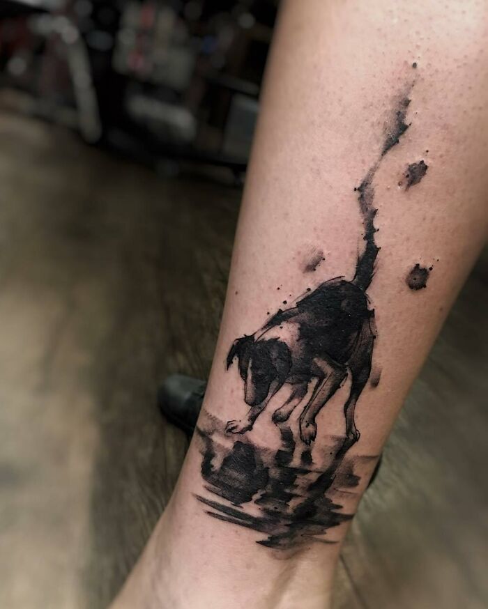 Tattoo of a dog gazing at its reflection, capturing a beautiful pet tribute on a person's leg.