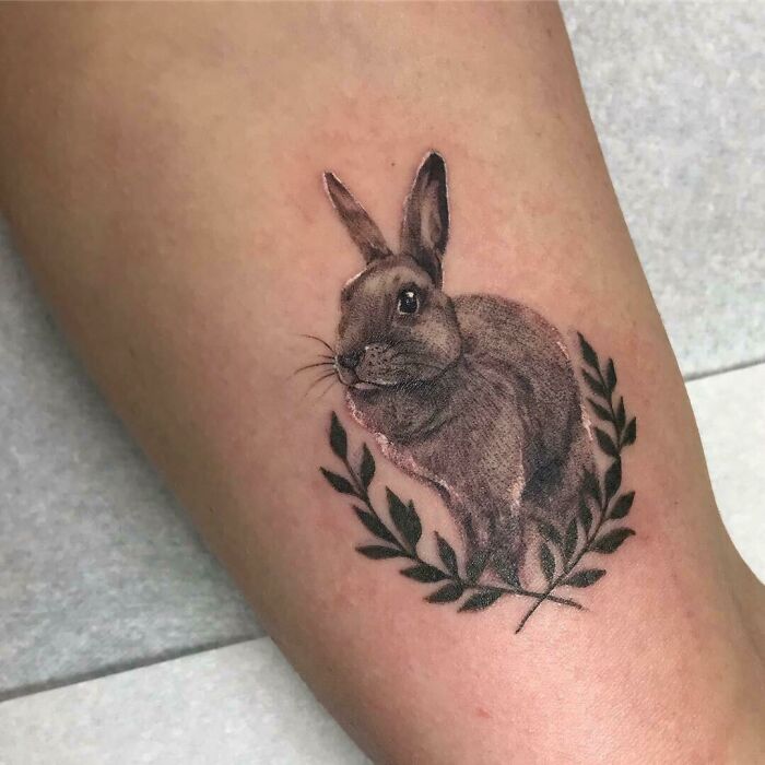 Rabbit pet tattoo design on forearm, showcasing a realistic rabbit surrounded by a laurel wreath.
