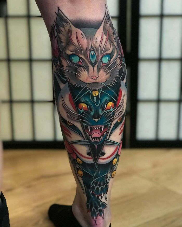 Colorful pet tattoo on a leg featuring an artistic design of a mystical cat with bold, vibrant details.