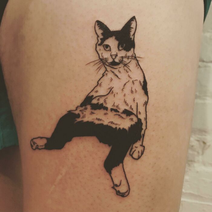 Pet tattoo of a relaxed black and white cat on skin, celebrating furry friends.