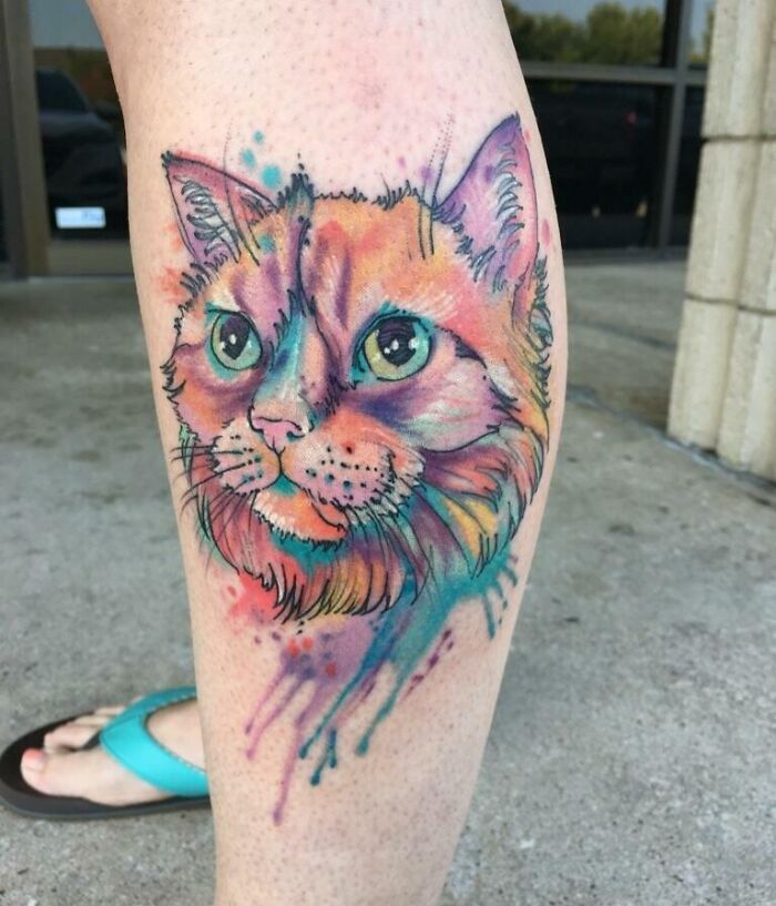 Colorful pet tattoo of a cat on a leg, celebrating the bond between humans and their pets.