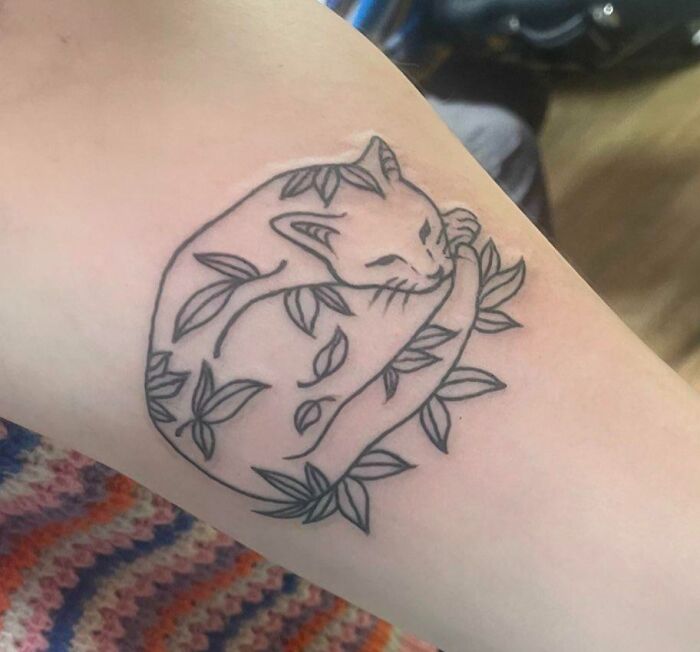 Pet tattoo of a cat entwined with leaves, illustrating the bond between humans and their pets.
