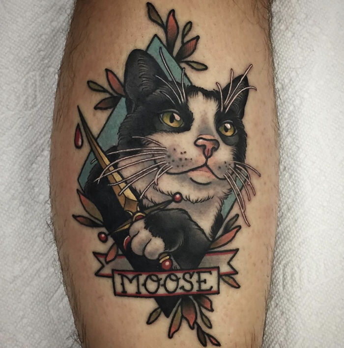 Cat pet tattoo with the name “Moose” on a person’s leg, showcasing a bond between humans and their pets.
