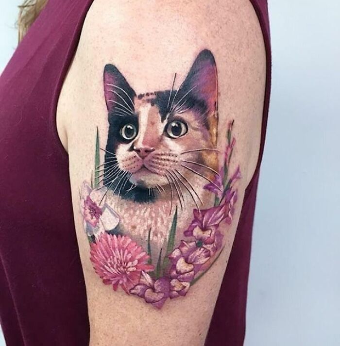Pet tattoo of a cat with colorful floral designs on an arm, highlighting the bond with a beloved animal companion.